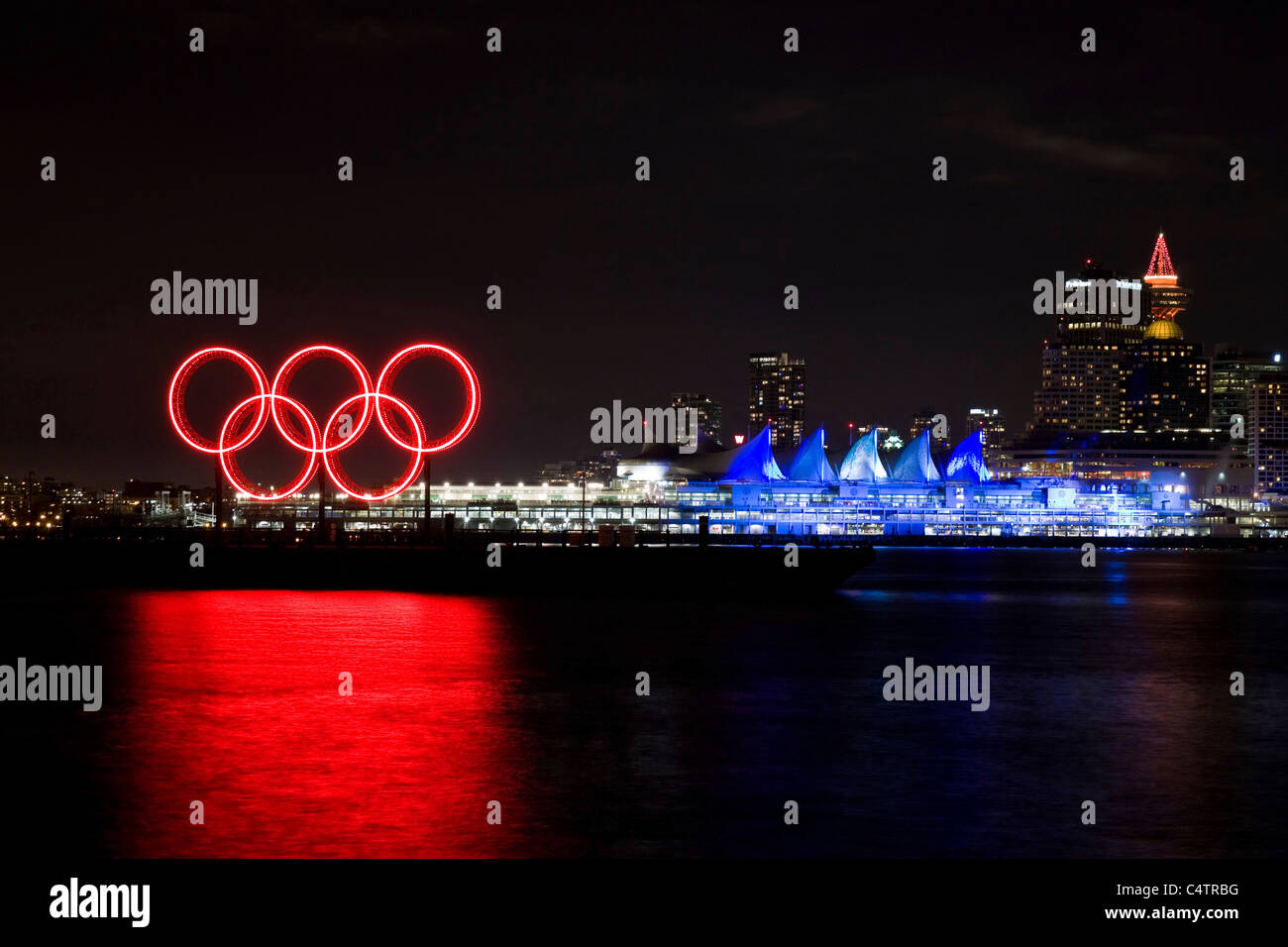 Red glowing Olympic rings and lit up Canada Place along the waterfront during the 2010 Winter Olympic Games, Vancouver, Canada Stock Photo
