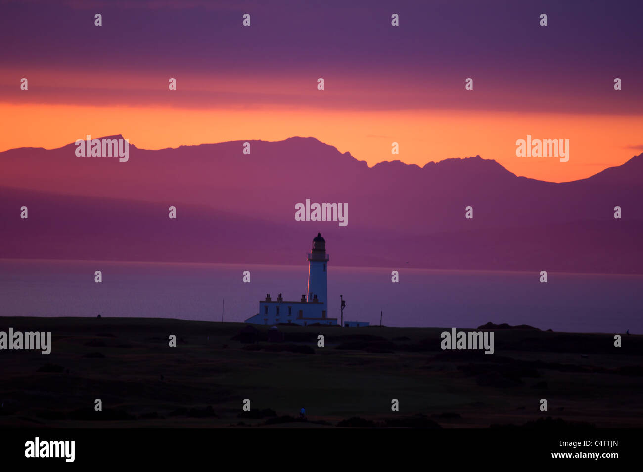 a lighthouse at dusk with an orange and purple sky Stock Photo