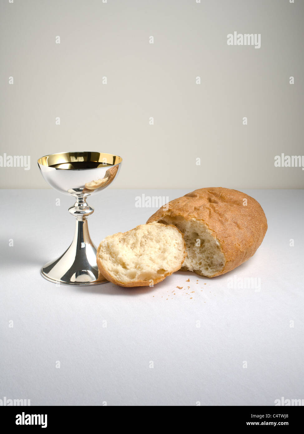 Holy Communion cup (chalice) with wine and broken loaf of bread, for celebration of Christian Holy Communion. Stock Photo
