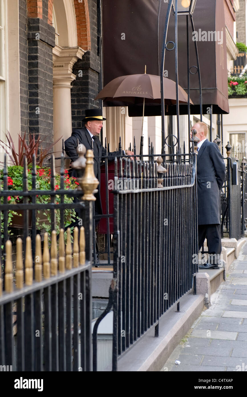 London Mayfair Curzon Street Aspinalls Gaming Club front door entrance laughing doormen in frock coats & top hat chatting grey frock coats Stock Photo