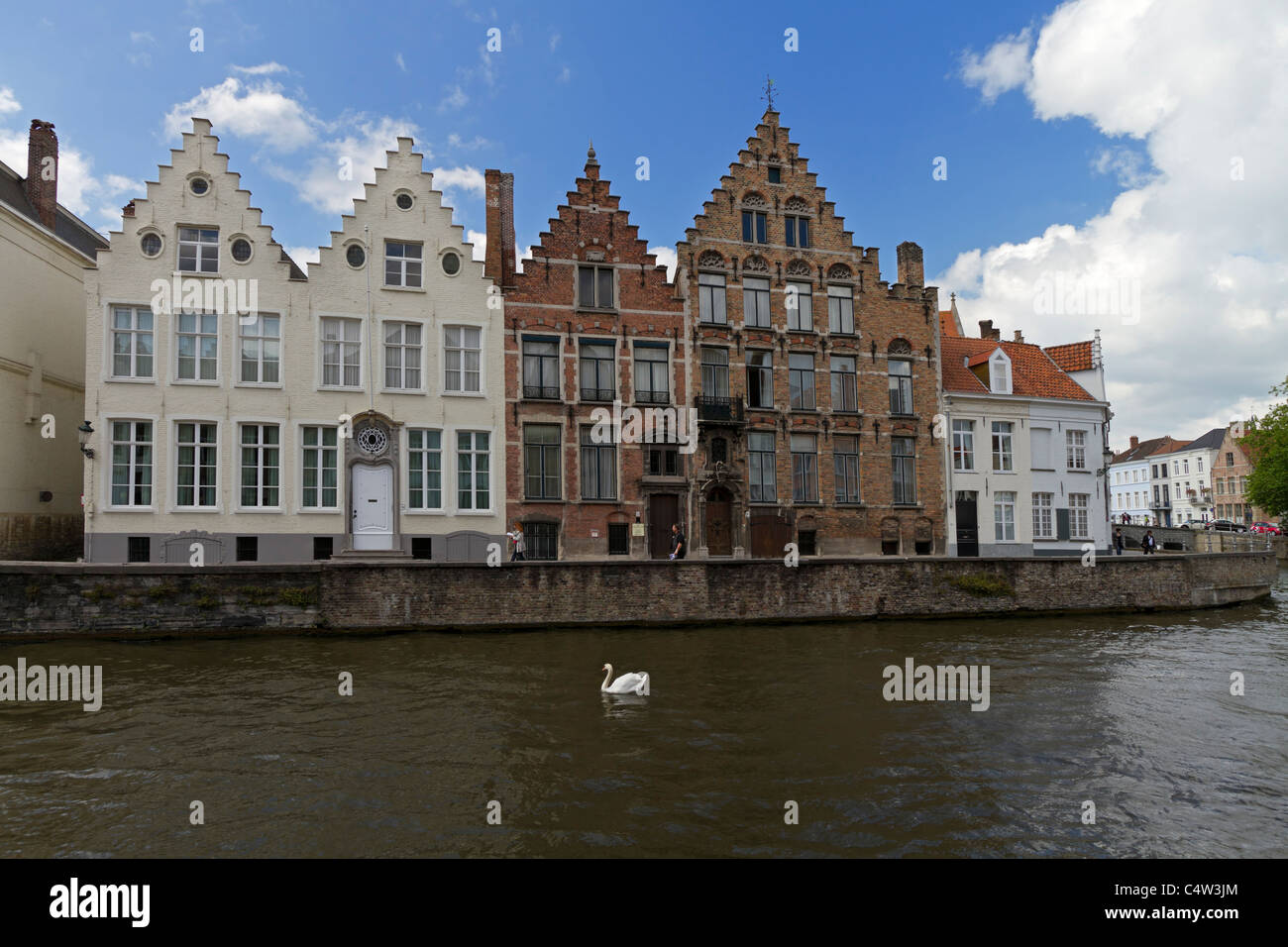 Spieglerei canal, Bruges, Belgium. A swan passes typical canalside houses with their stepped gables and medieval architecture. Stock Photo
