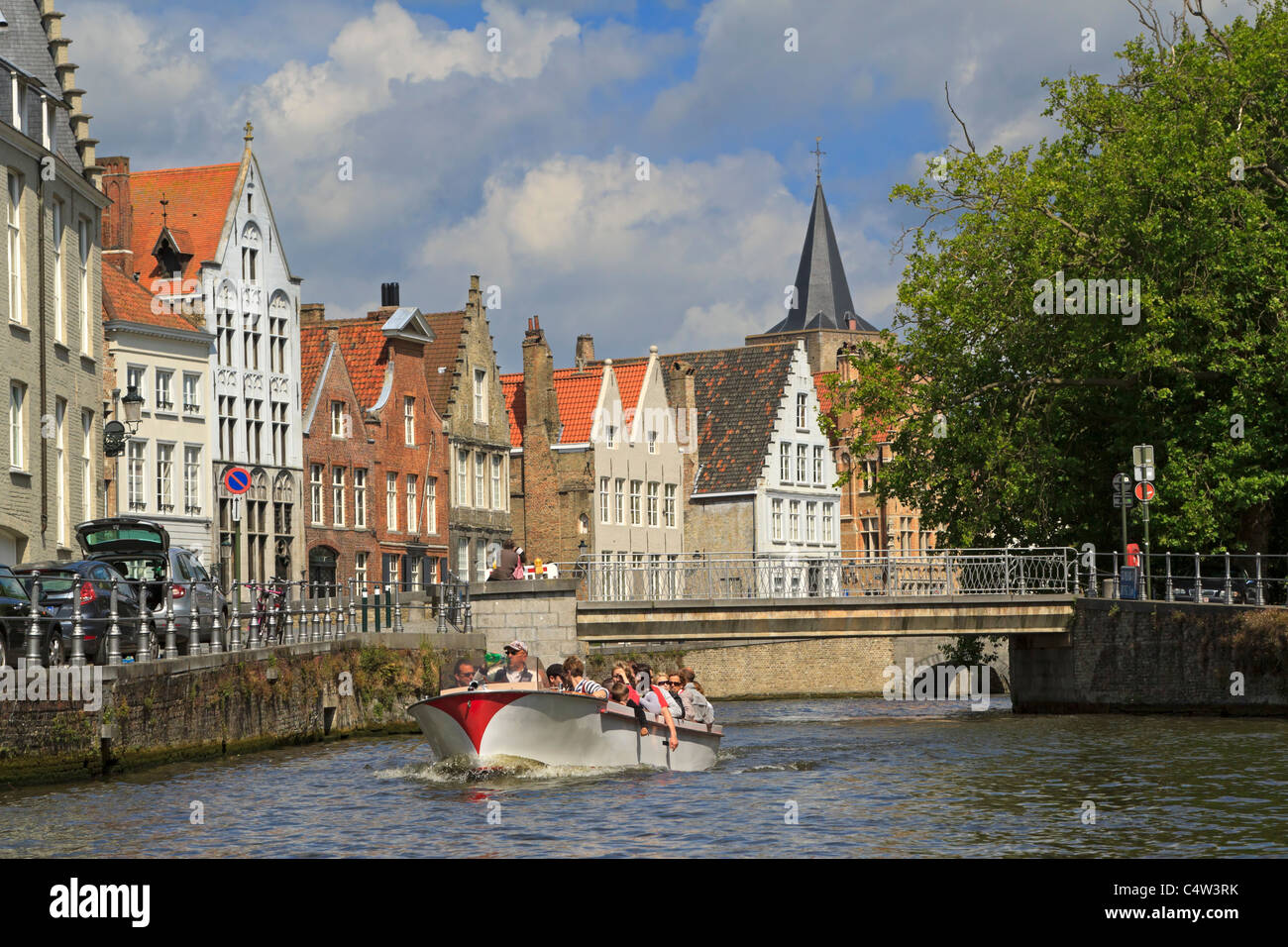 Verversdijk, Bruges, Belgium. Tourist enjoy a tour of the canal in a sightseeing boat. Stock Photo