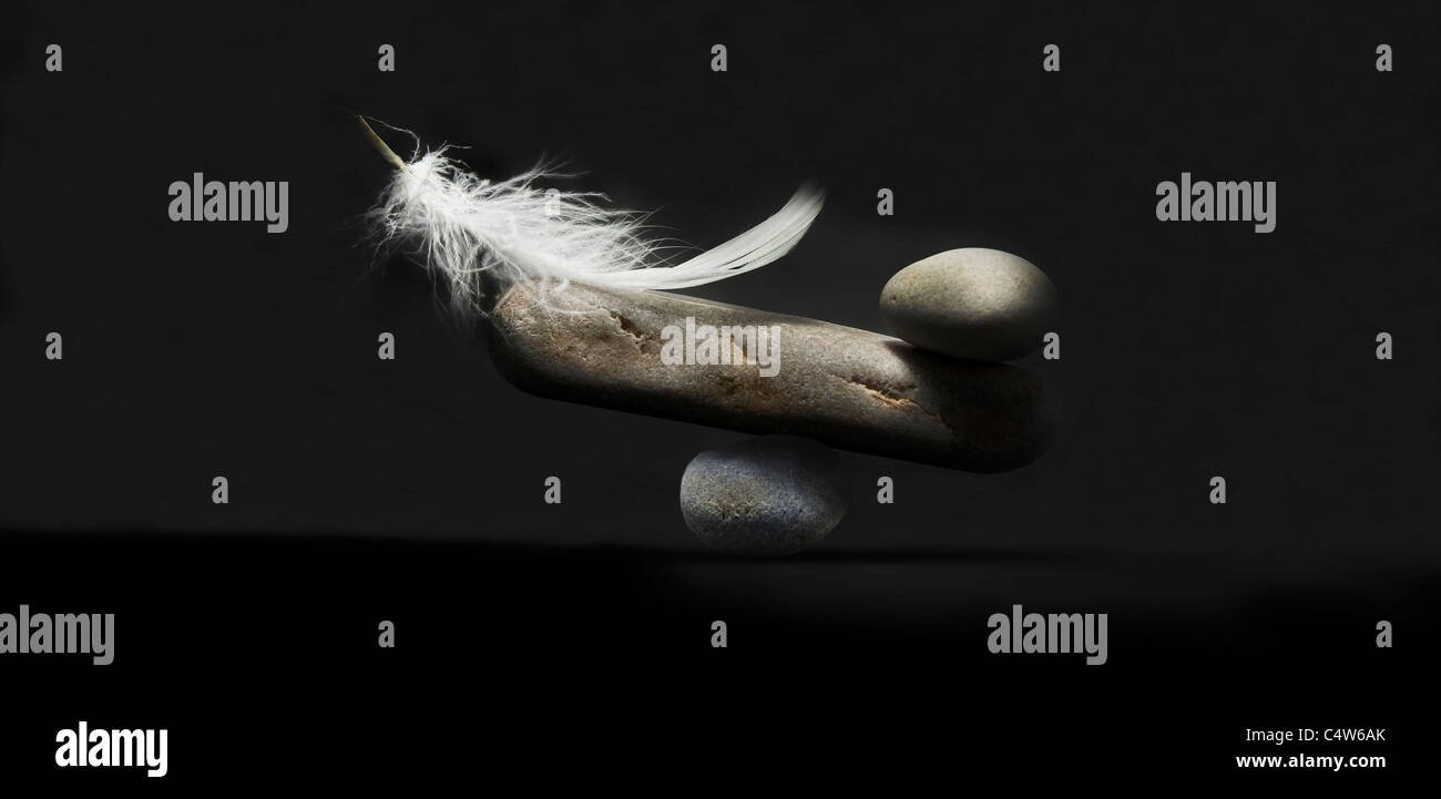 black background feather and stone balance Stock Photo