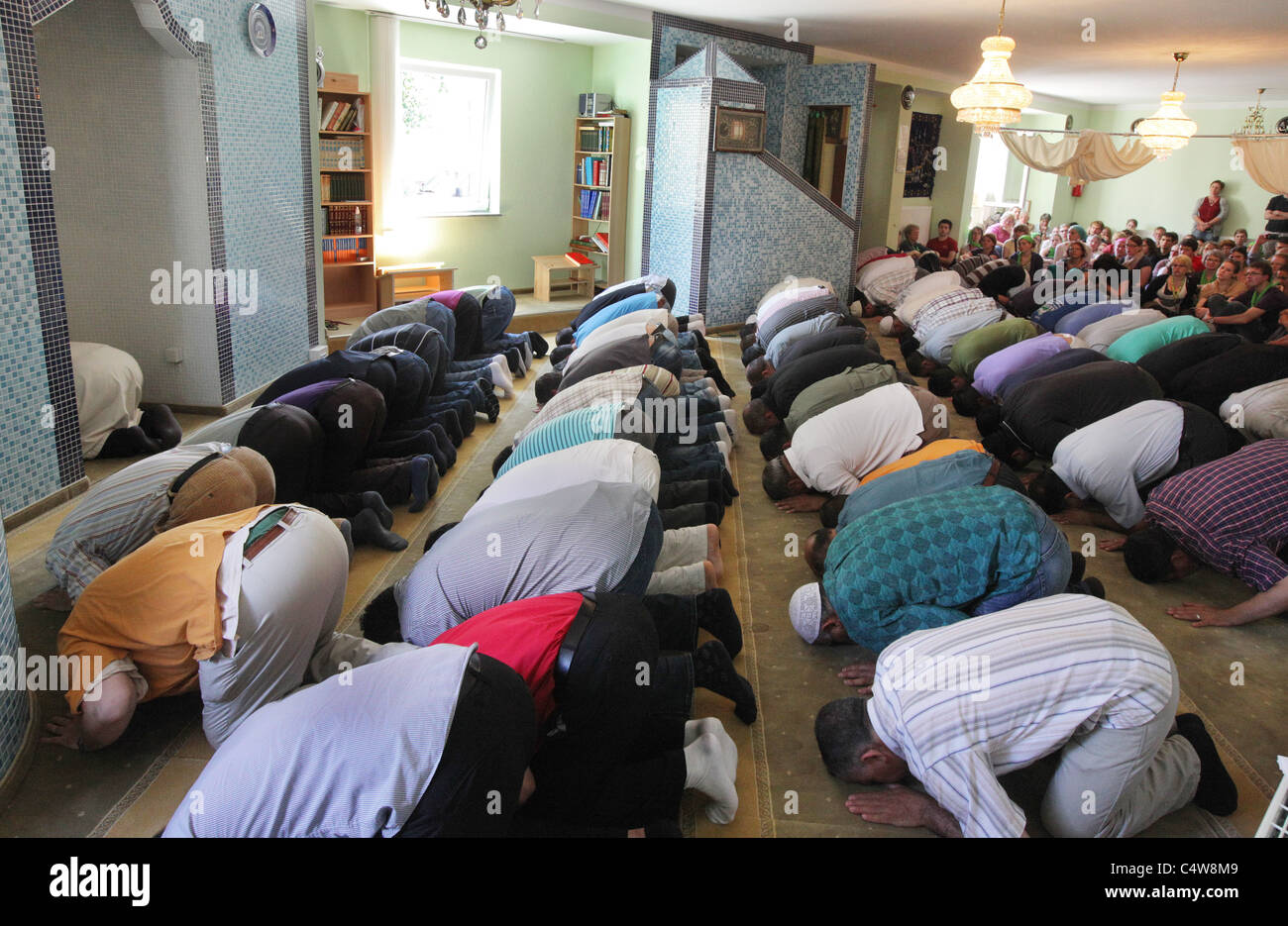 turkish muslims (front) watched by german christians (back) during a friday prayer in a mosque in Dresden, Germany. Stock Photo