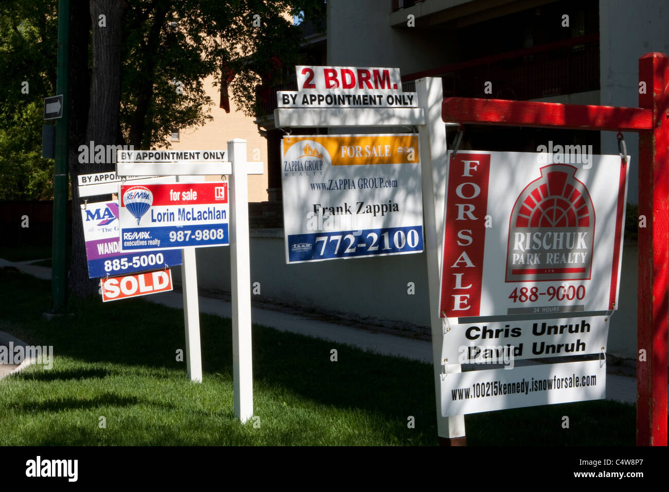 "For sale" signs for Maximum realty, Re/Max, Zappia Group realty and Rischuk Park realty are seen next to each other in Winnipeg Stock Photo