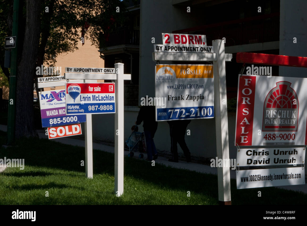 Maximum realty, Re/Max, Zappia Group realty and Rischuk Park realty 'For sale' signs are seen next to each other in Winnipeg Stock Photo