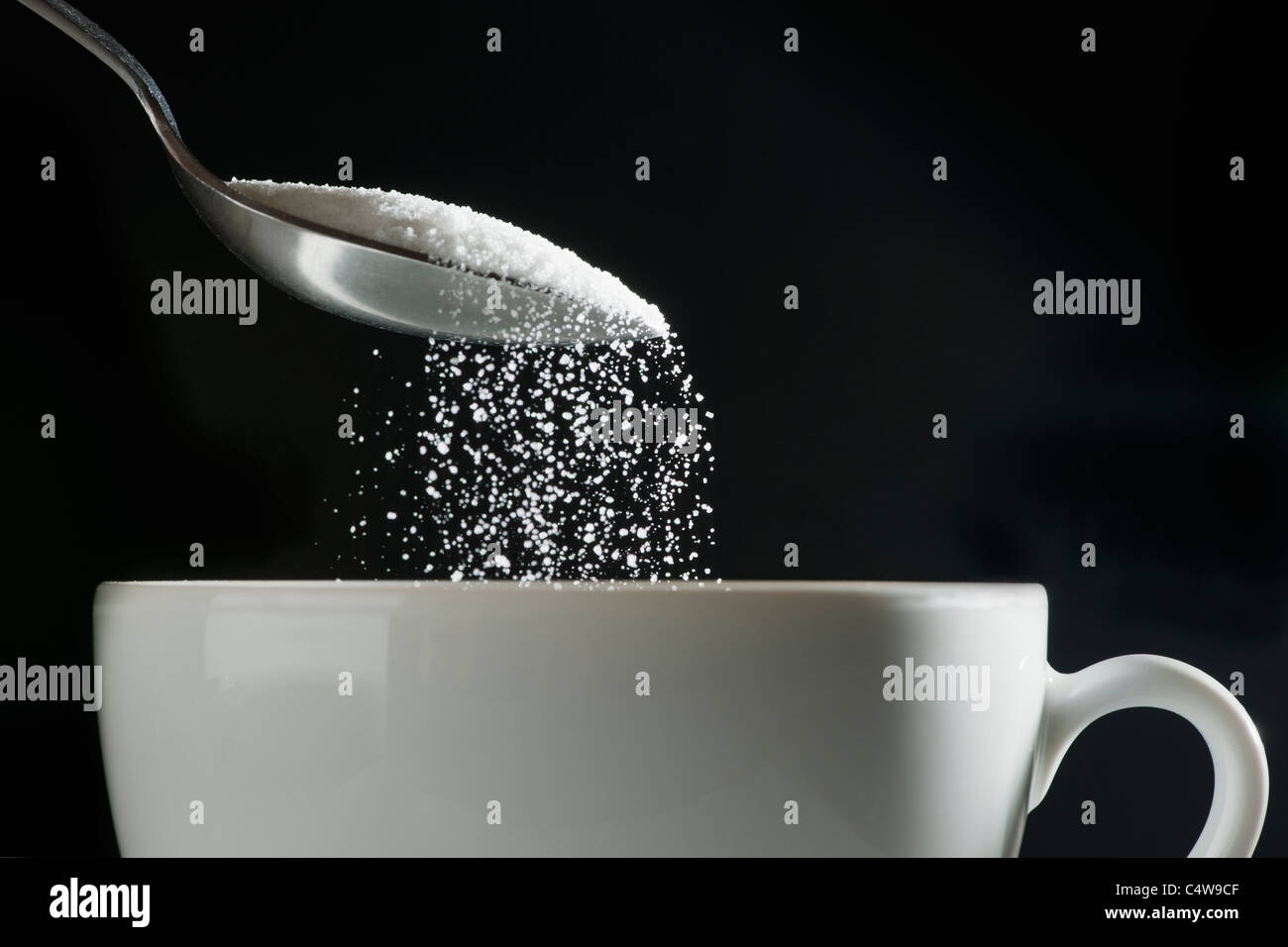 Studio shot of sugar poured into coffee cup Stock Photo