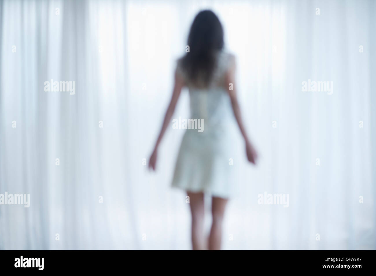 USA, New Jersey, Jersey City, Young woman standing and looking through window Stock Photo