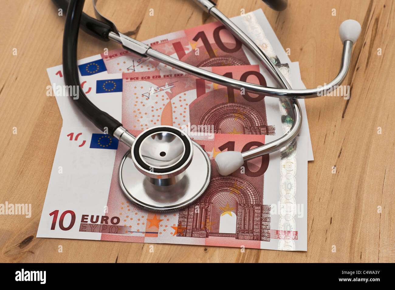 ein Stethoskop liegt auf mehreren zehn Euro Scheinen | some ten euro banknotes, a stethoscope is on it Stock Photo