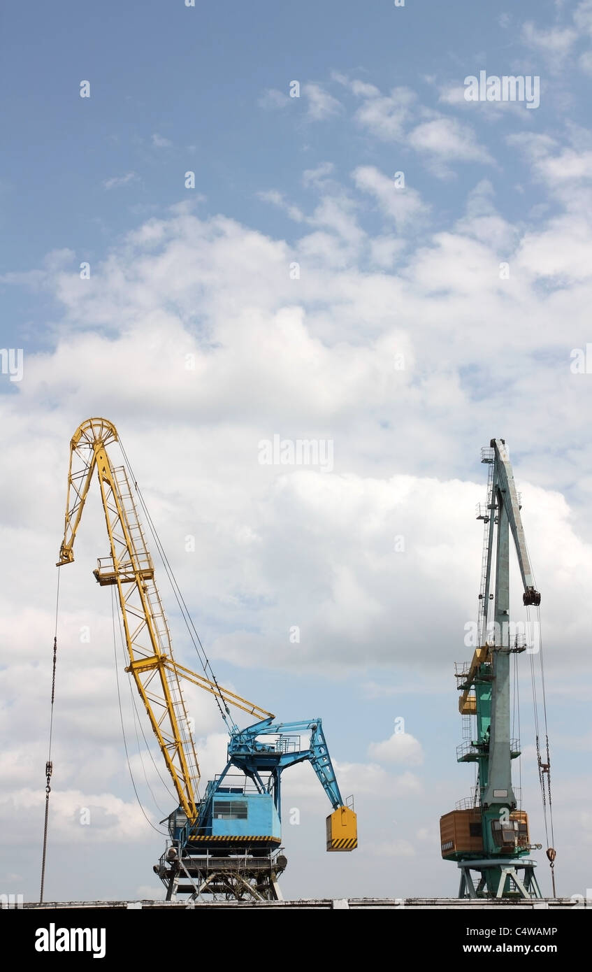Two elevating cranes in river port against the sky Stock Photo