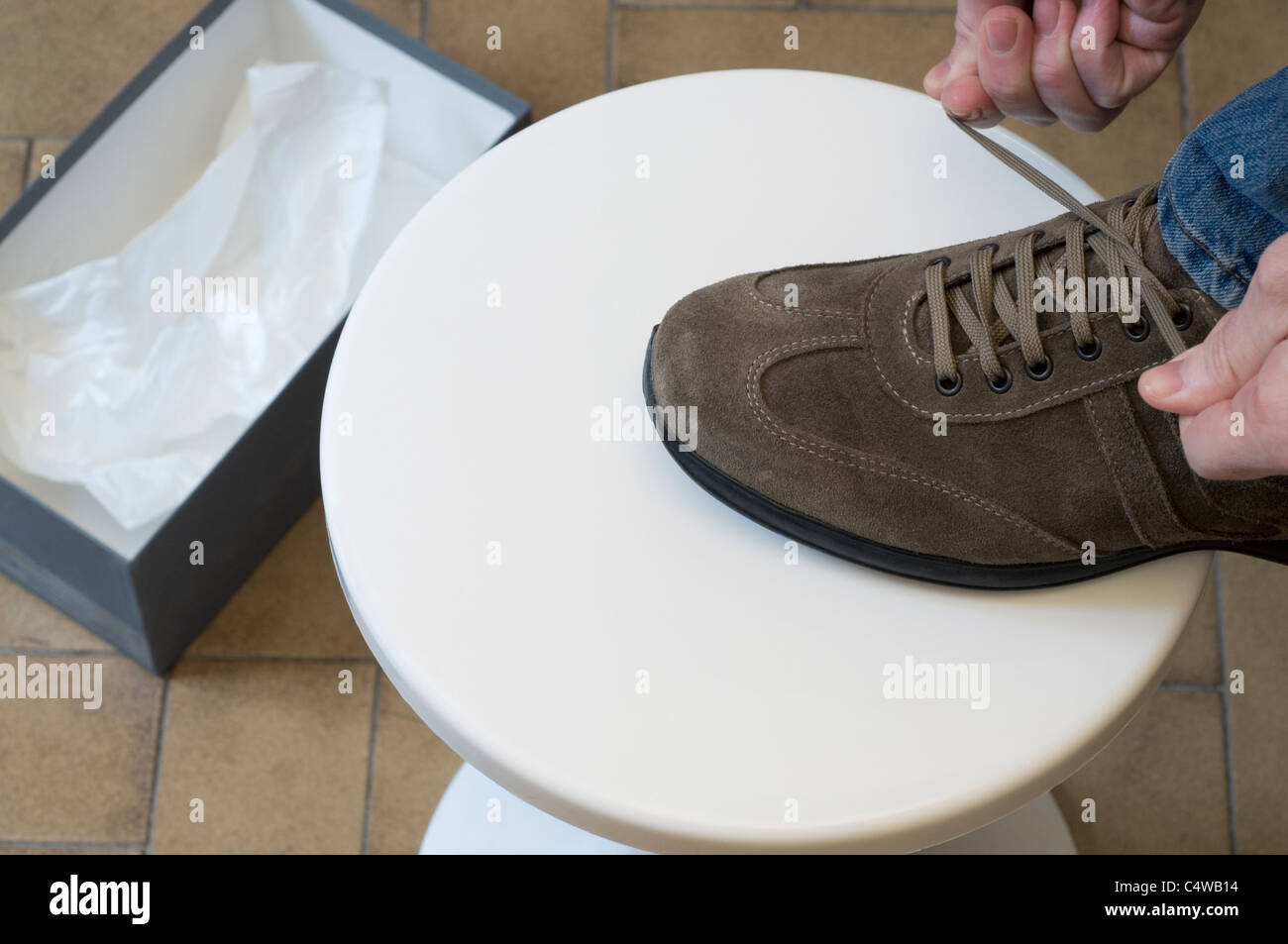 Man Tying Shoe on Stool and Empty Box Stock Photo Alamy
