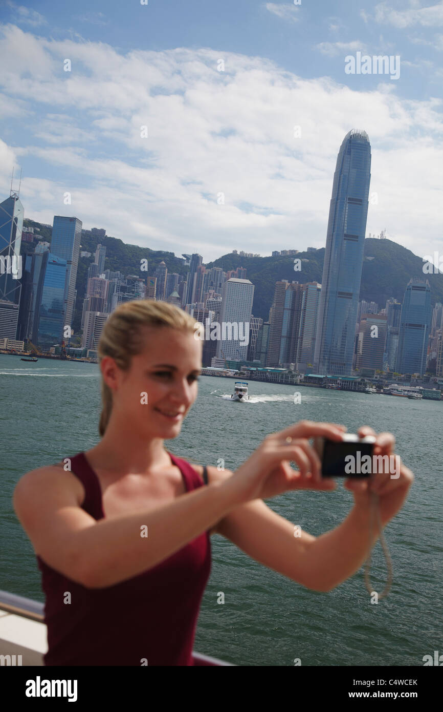 Woman taking photo of herself in front of Hong Kong skyline, Hong Kong ...