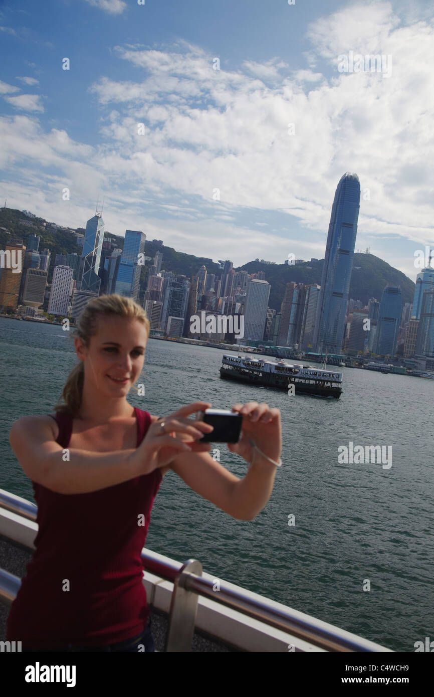 Woman taking photo of herself in front of Hong Kong skyline, Hong Kong ...