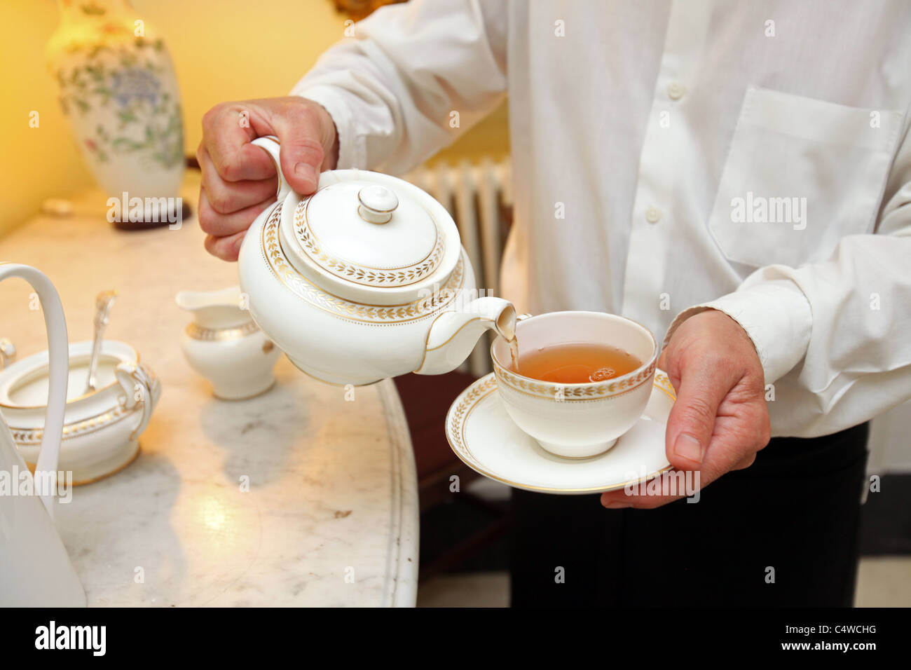 Waiter pouring tea into teacup. Stock Photo