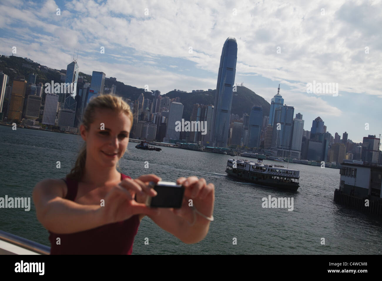 Woman taking photo of herself in front of Hong Kong skyline, Hong Kong ...