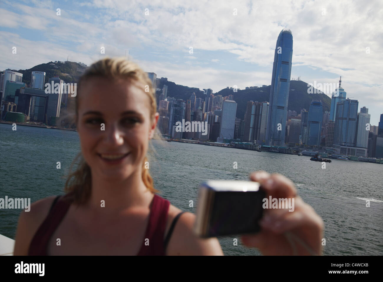 Woman taking photo of herself in front of Hong Kong skyline, Hong Kong ...