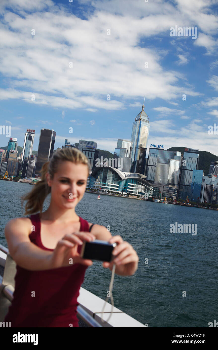 Woman taking photo of herself in front of Hong Kong skyline, Hong Kong ...