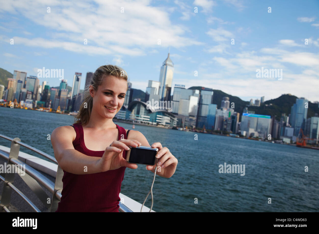 Woman taking photo of herself in front of Hong Kong skyline, Hong Kong ...