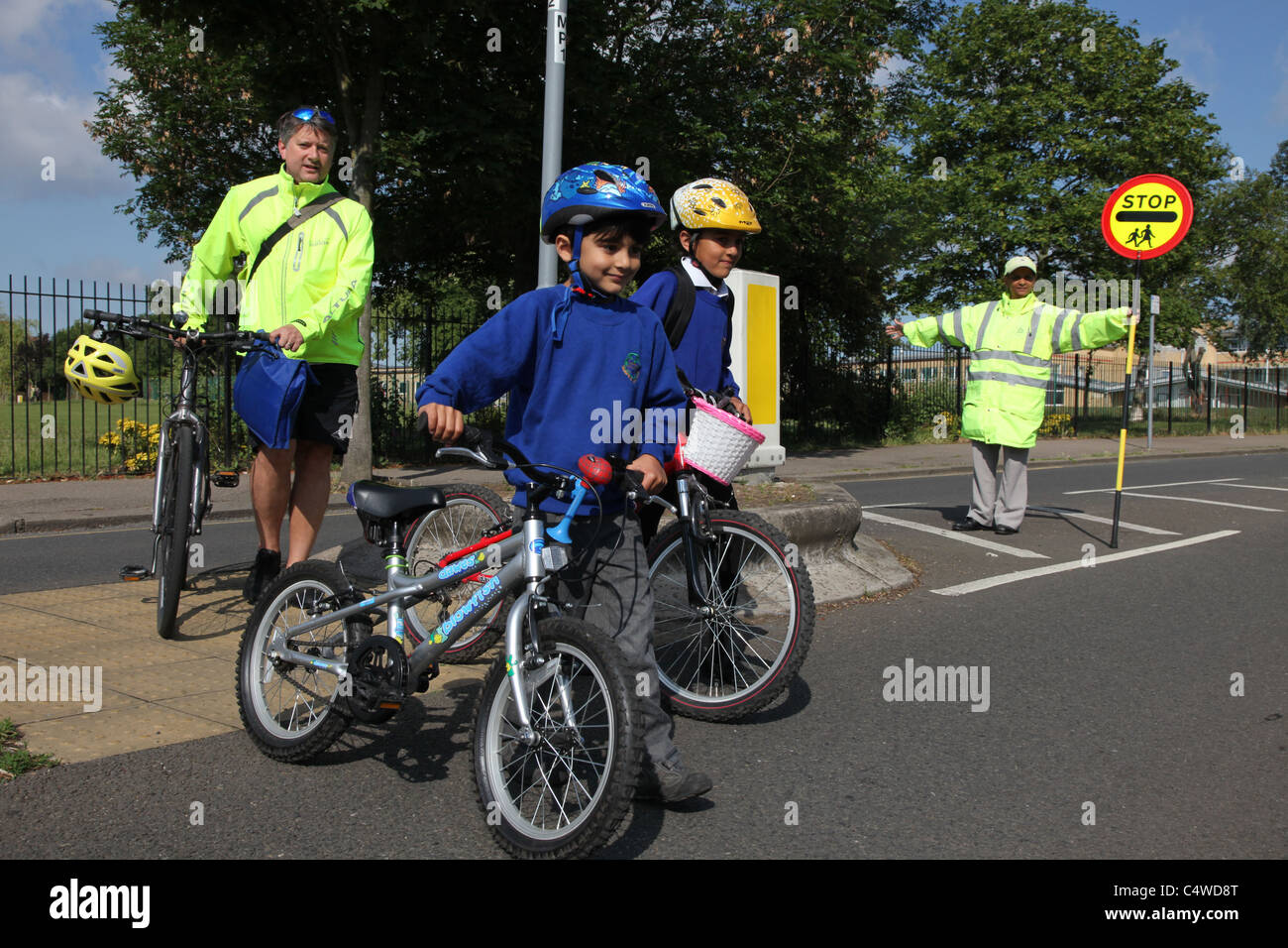 A lollipop lady helps school children cross the road safely Stock Photo