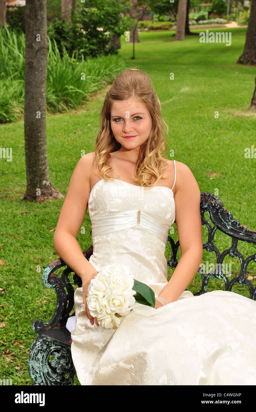 A pretty Caucasian bride is sitting out on a park bench Stock Photo