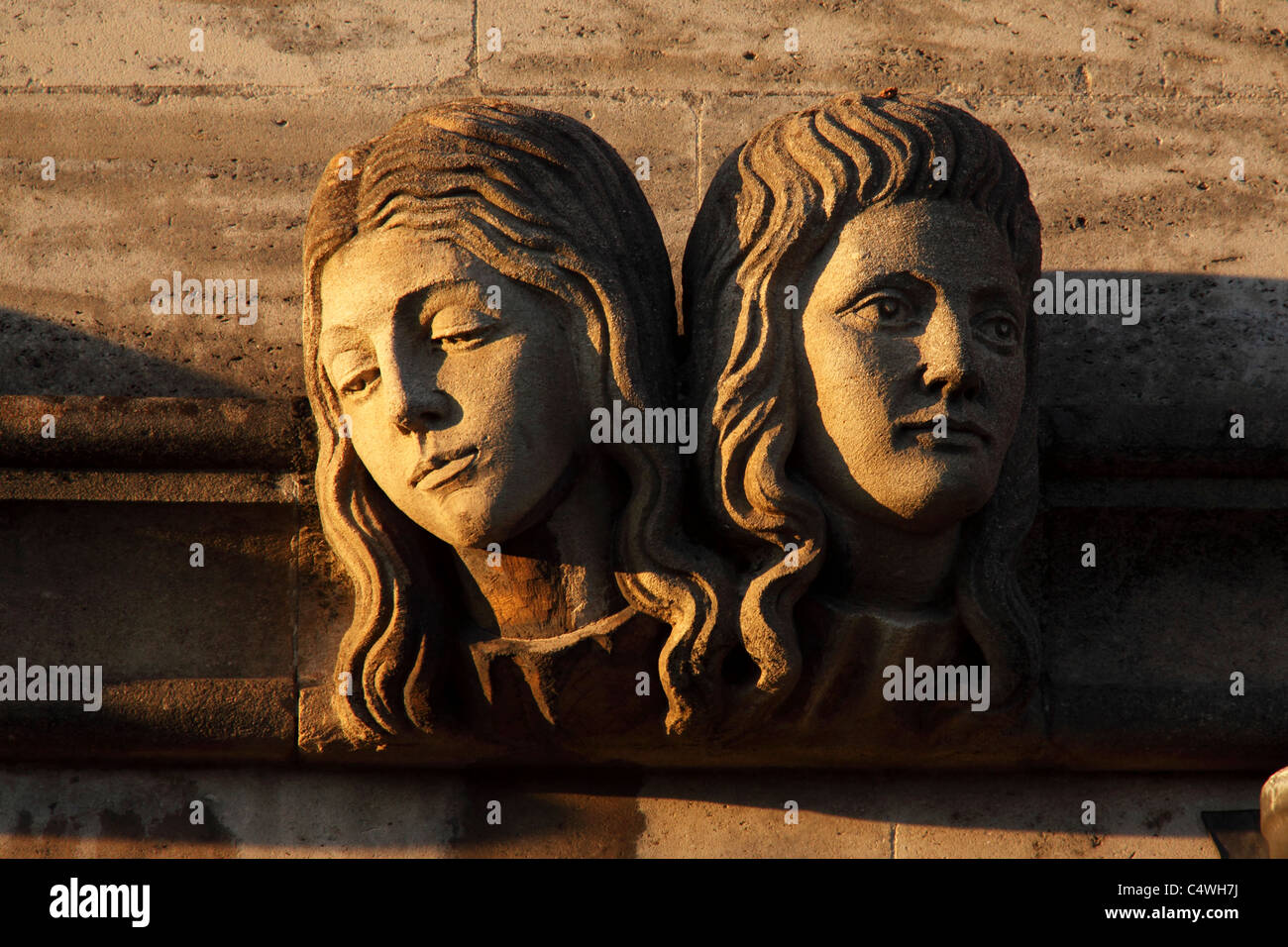 Two female heads, a gargoyle on the exterior of Magdalen College in Oxford, England. Stock Photo