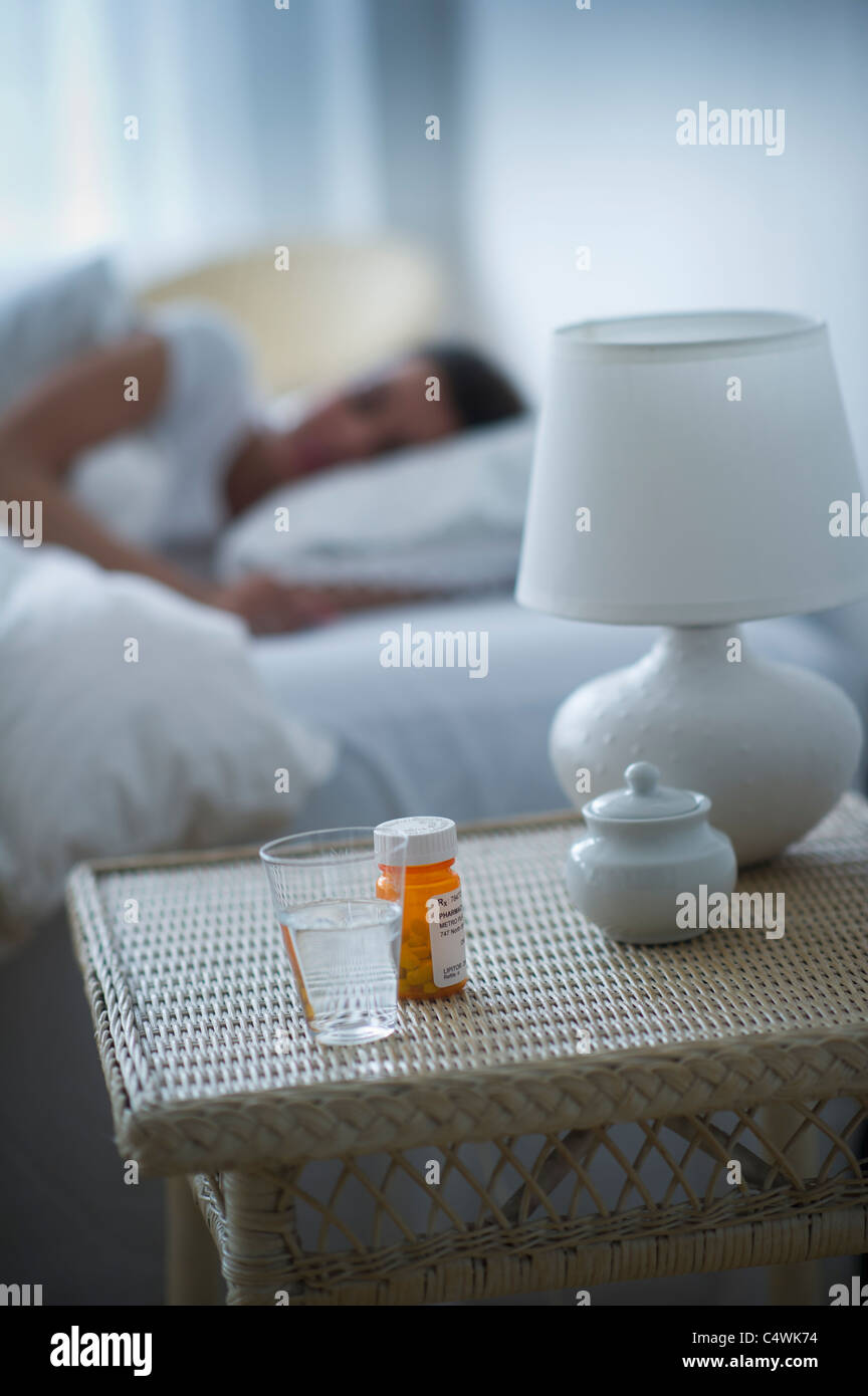 USA, New Jersey, Jersey City, Sleeping pills bedside table with woman sleeping in background Stock Photo