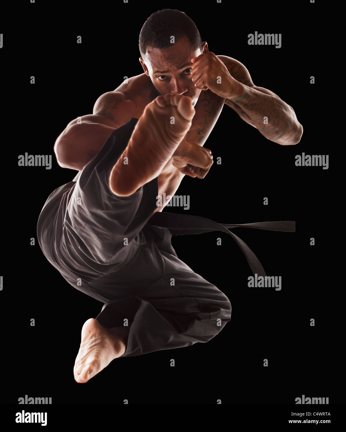 Studio shot of martial arts practitioner in mid-air kick Stock Photo