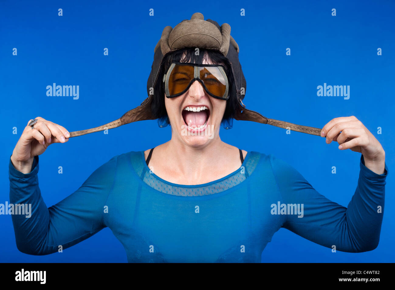 woman with old army tank personal helmet, laughing - isolated on blue Stock Photo