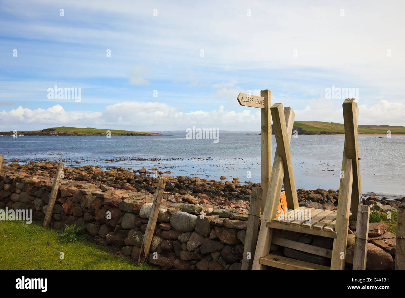 Ness of Melby, Sandness, Shetland Islands, Scotland, UK. Sandness coastal walkway sign and stile with view to Melby Holm island Stock Photo