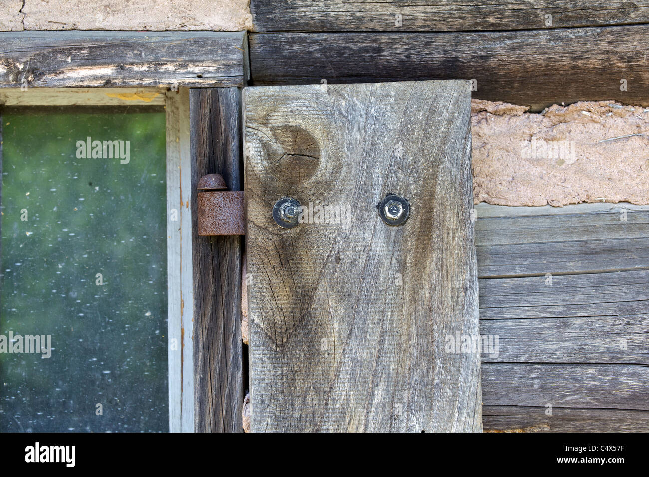 Rustic Rusted Window Hinge on a Weathered Log Cabin Stock Photo