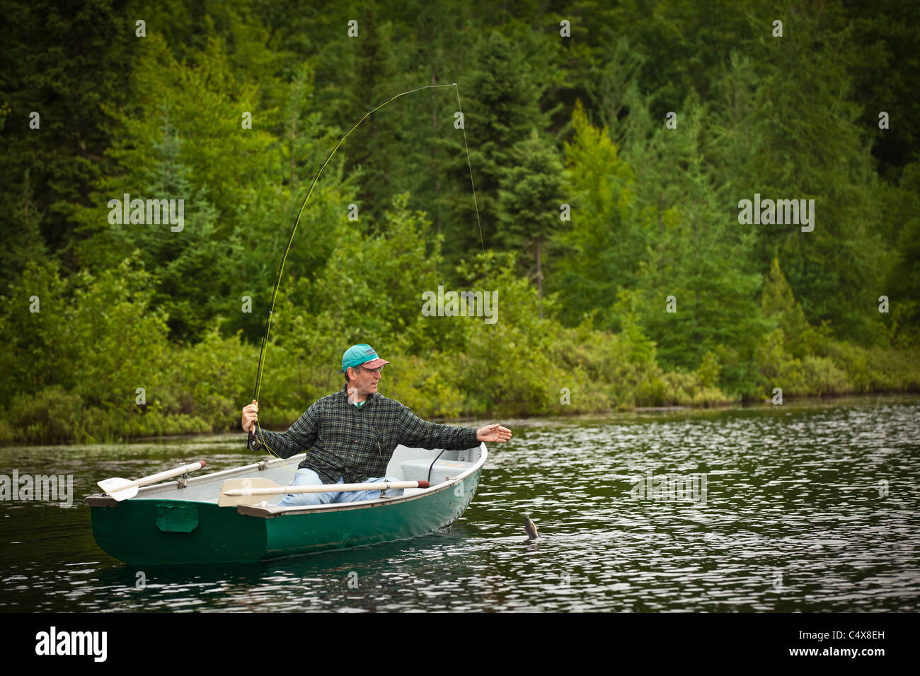 A man pulls in a trout caught fishing on a lake in Boulder Junction
