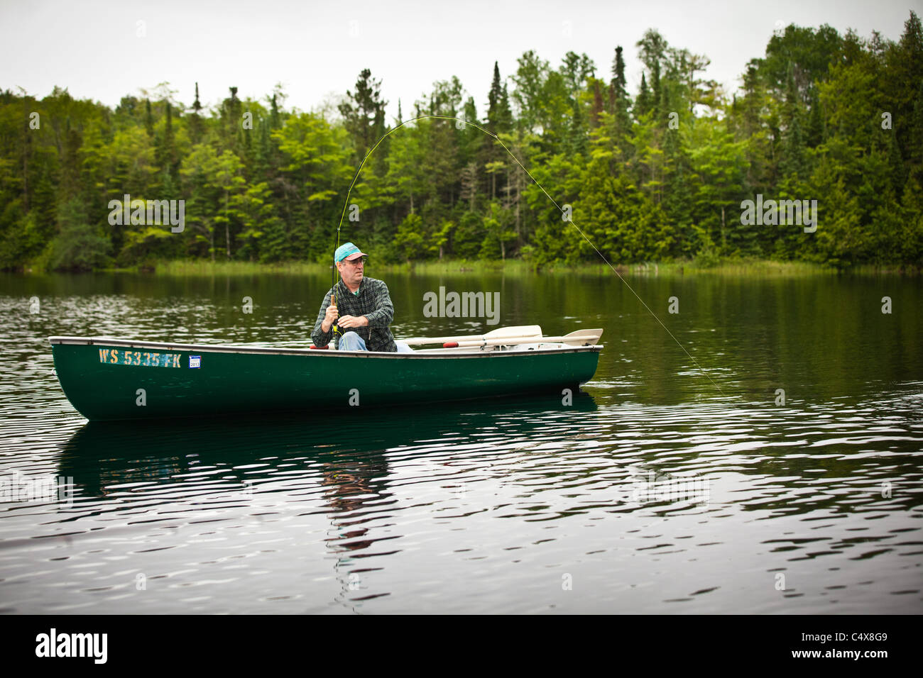 A man pulls in a trout caught fishing on a lake in Boulder Junction