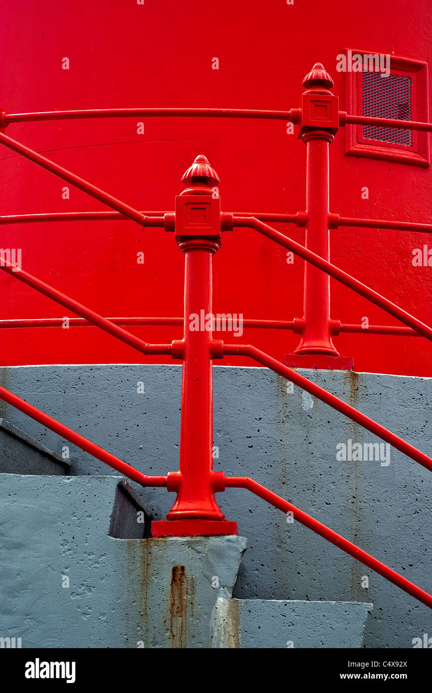 Abstract architectural detail photo of a set of concrete stairs with bright red railings against a bright red wall. Stock Photo