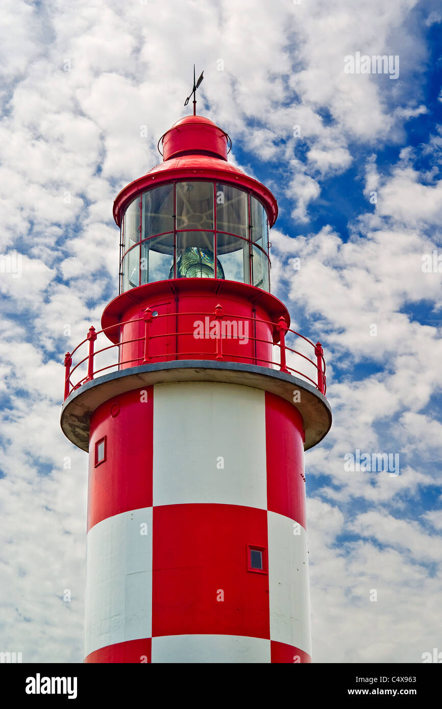 Looking up at an old, red and white historic maritime lighthouse in daytime. Stock Photo