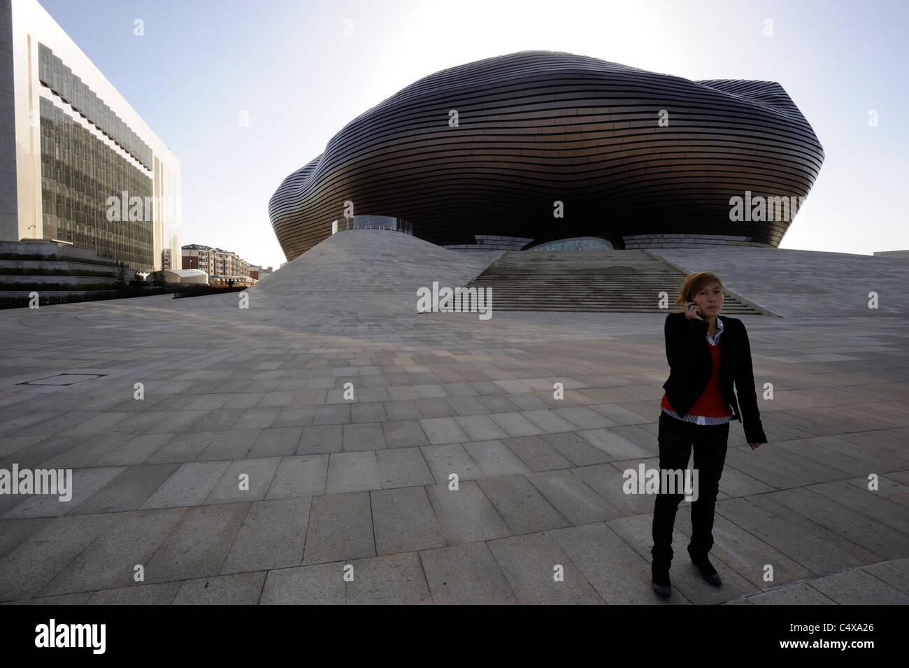 A lady speaks on mobile phone in front of the new museum in Kangbashi, Ordos, Inner Mongolia, China. 12-May-2011 Stock Photo