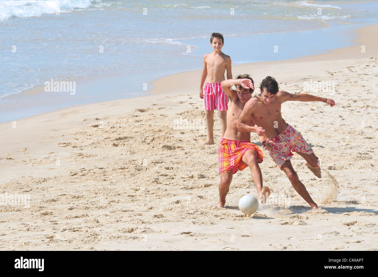Israeli boys play football in the hot weather in Nitzanim beach, Israel. Stock Photo