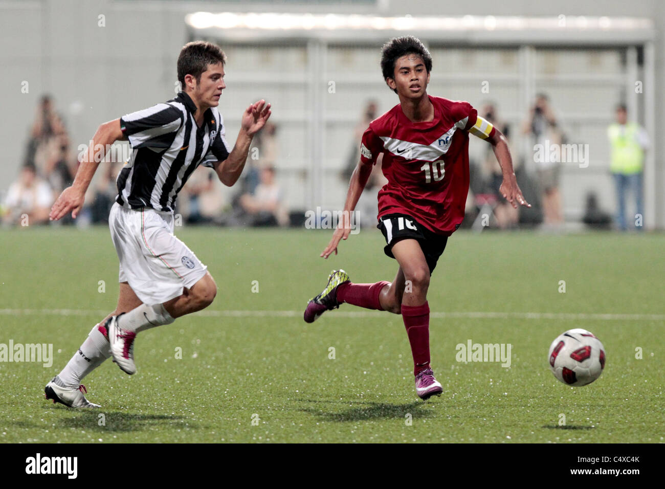 Adam Swandi of Singapore U15(red) and Crepaldi Federico chase down the loose ball during the 23rd Canon Lion City Cup Stock Photo