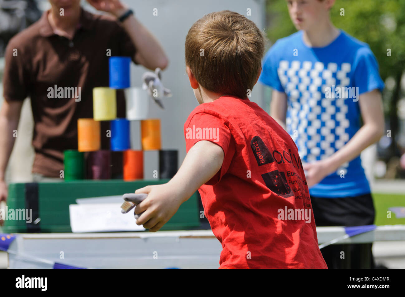 Boy throws bean bag at tins in fairground game 'Tin Can Alley' Stock Photo