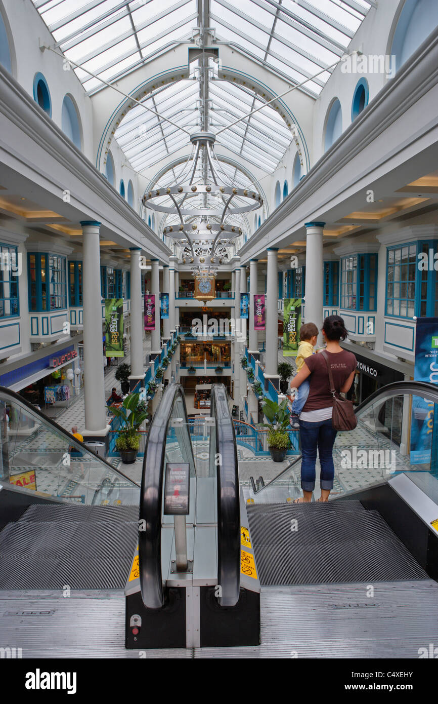 Mother and child going down escalator in large downtown shopping mall in city-Victoria, British Columbia, Canada. Stock Photo