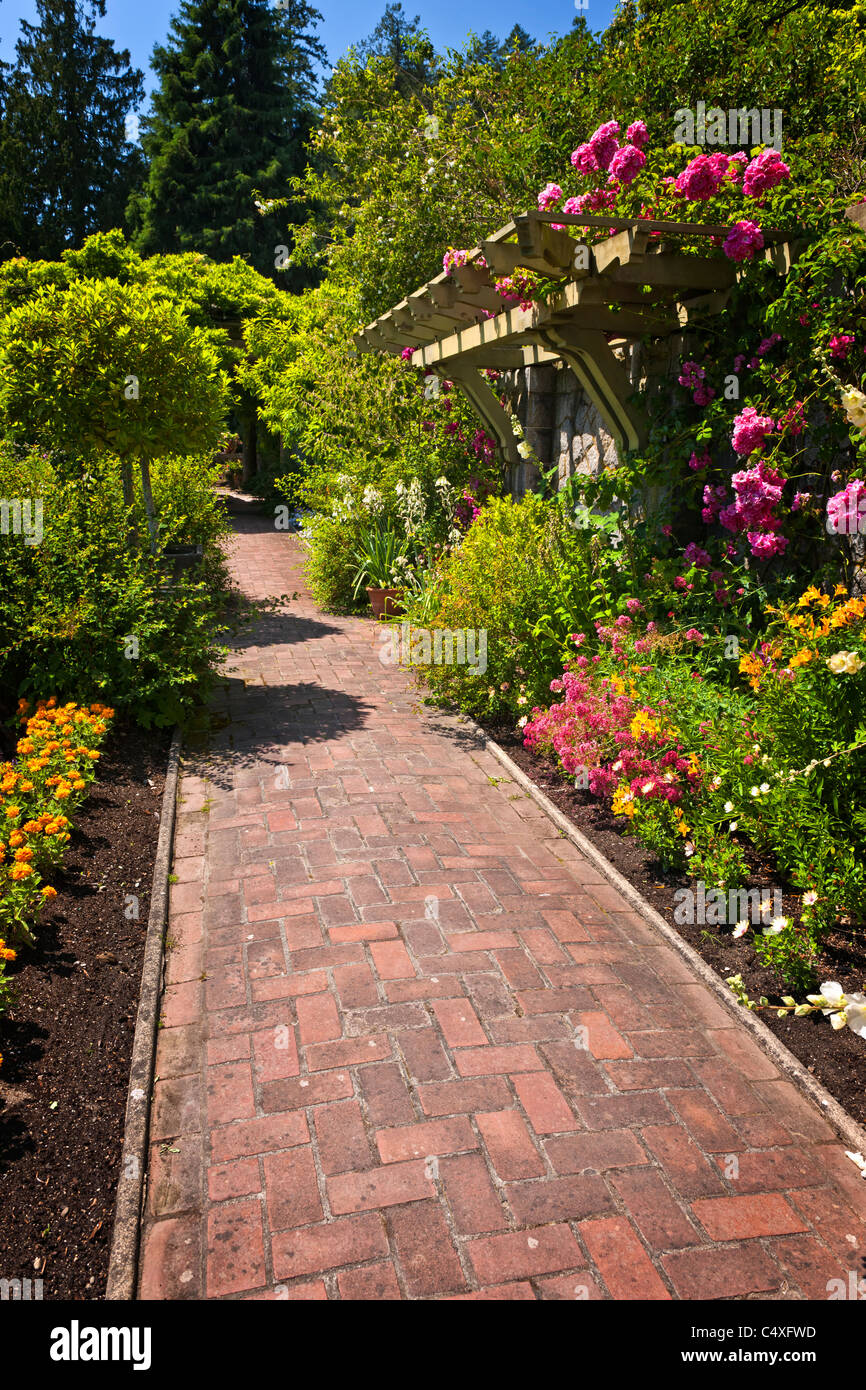 Lush summer garden with paved path and blooming flowers Stock Photo