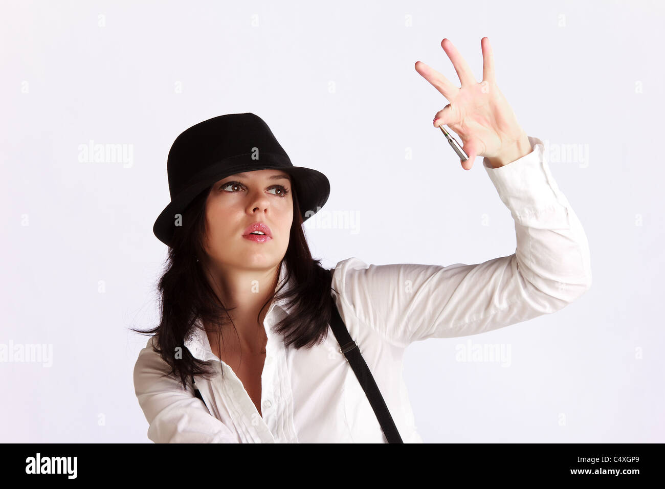 Young woman in hat with brim holding a machine-gun ammo between her fingers Stock Photo