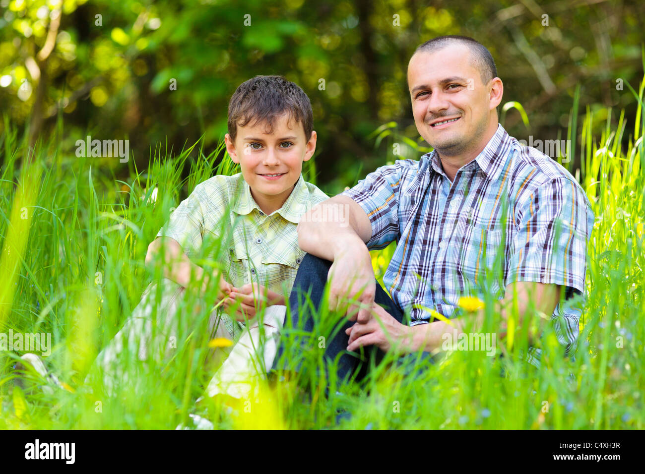 Father and son sitting in grass on a meadow Stock Photo - Alamy