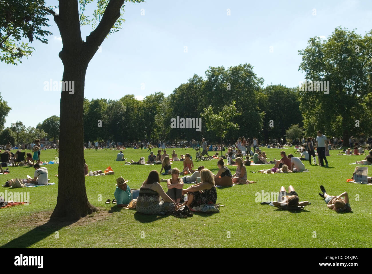 Queens Park north London UK crowds of people enjoying summer sunshine relaxing HOMER SYKES Stock Photo
