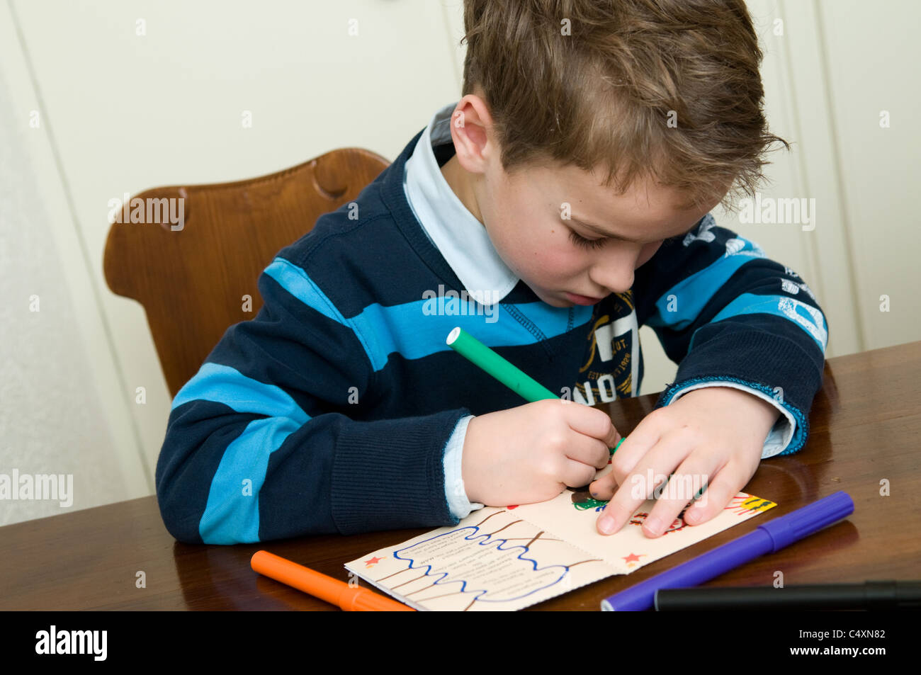 Young boy writing and drawing on a piece of paper Stock Photo - Alamy