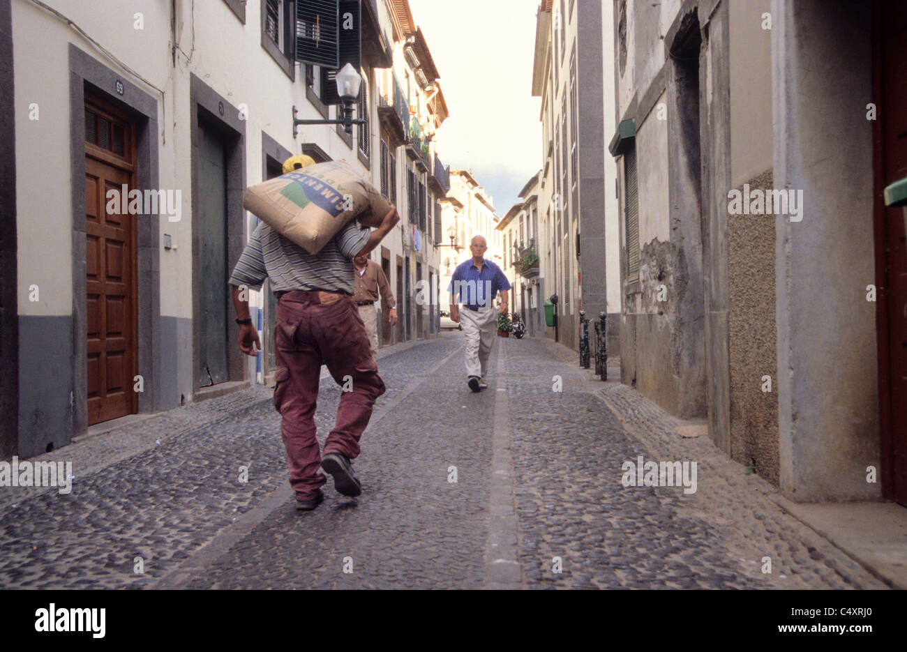 Man carrying a bag of cement in the centre of Funchal, along Rua De
