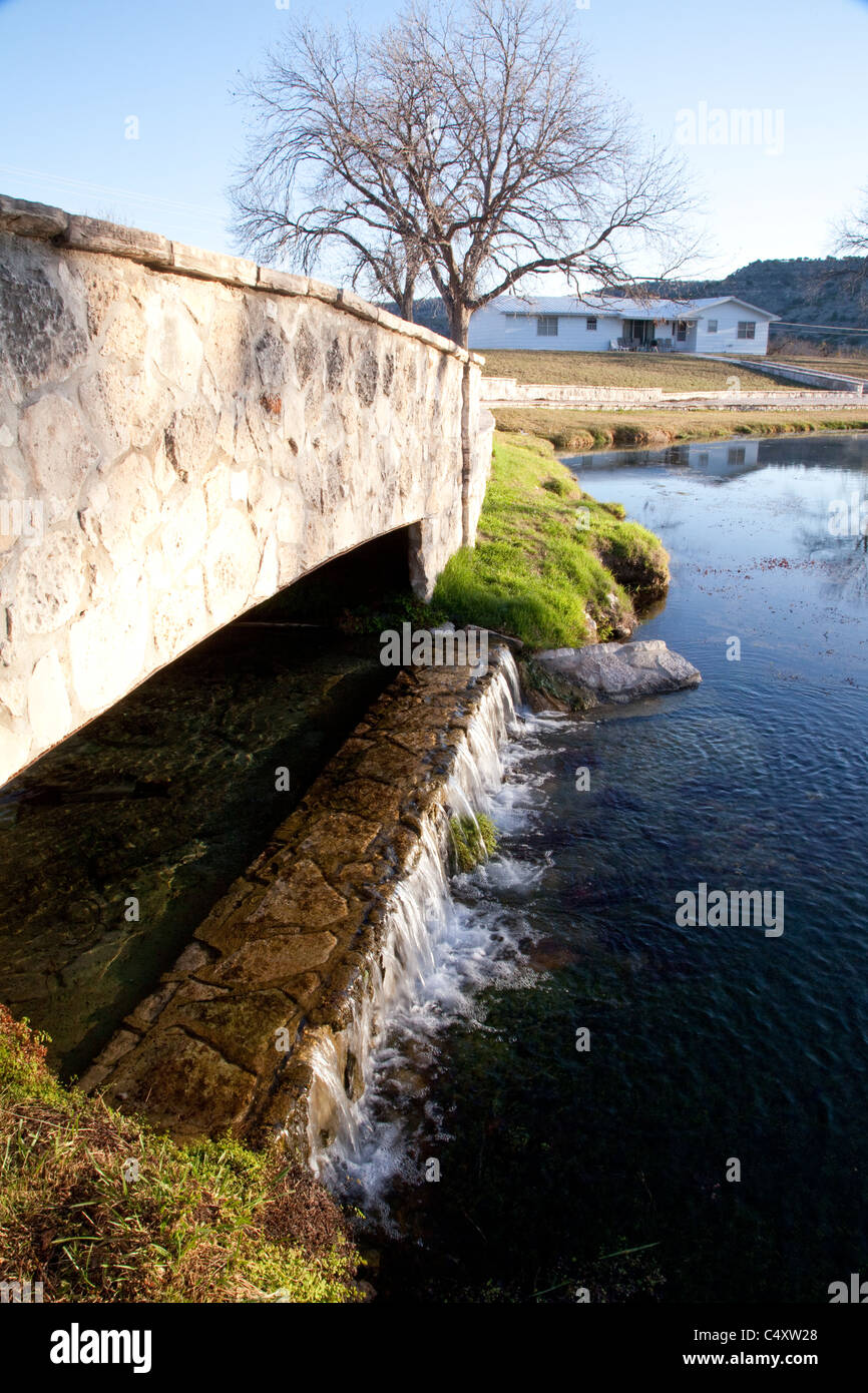 Clear spring water flows over low waterfall into small springfed lake at Independence Creek
