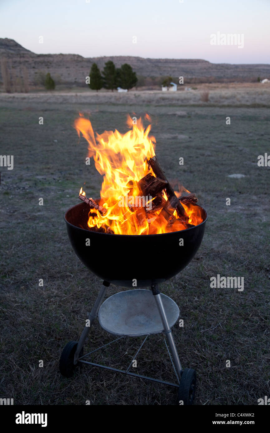 Small branches burn in a kettlestyle charcoal grill before supper at Independence Creek nature