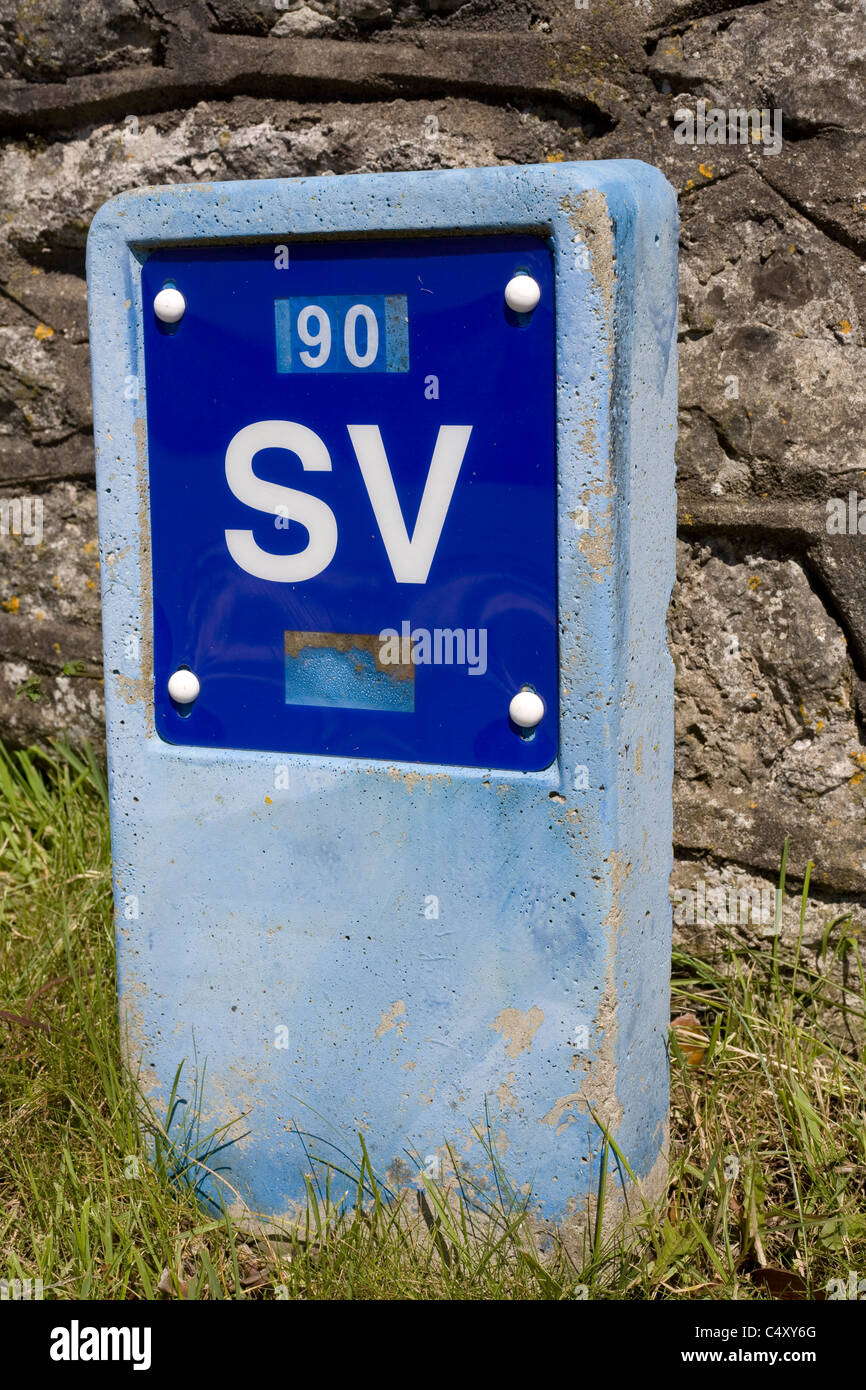 blue concrete marker of sluice valve giving distance in millimetres to the water main Stock Photo