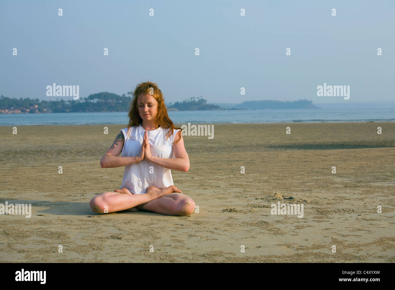 A young woman performs a yoga meditation pose at a beach Stock Photo ...