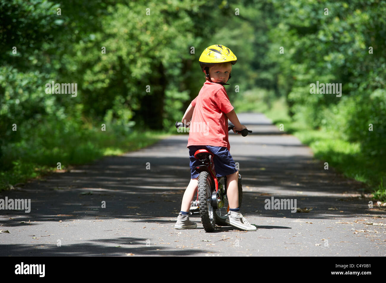 Child blond boy 4 years old riding bicycle with safety helmet in park